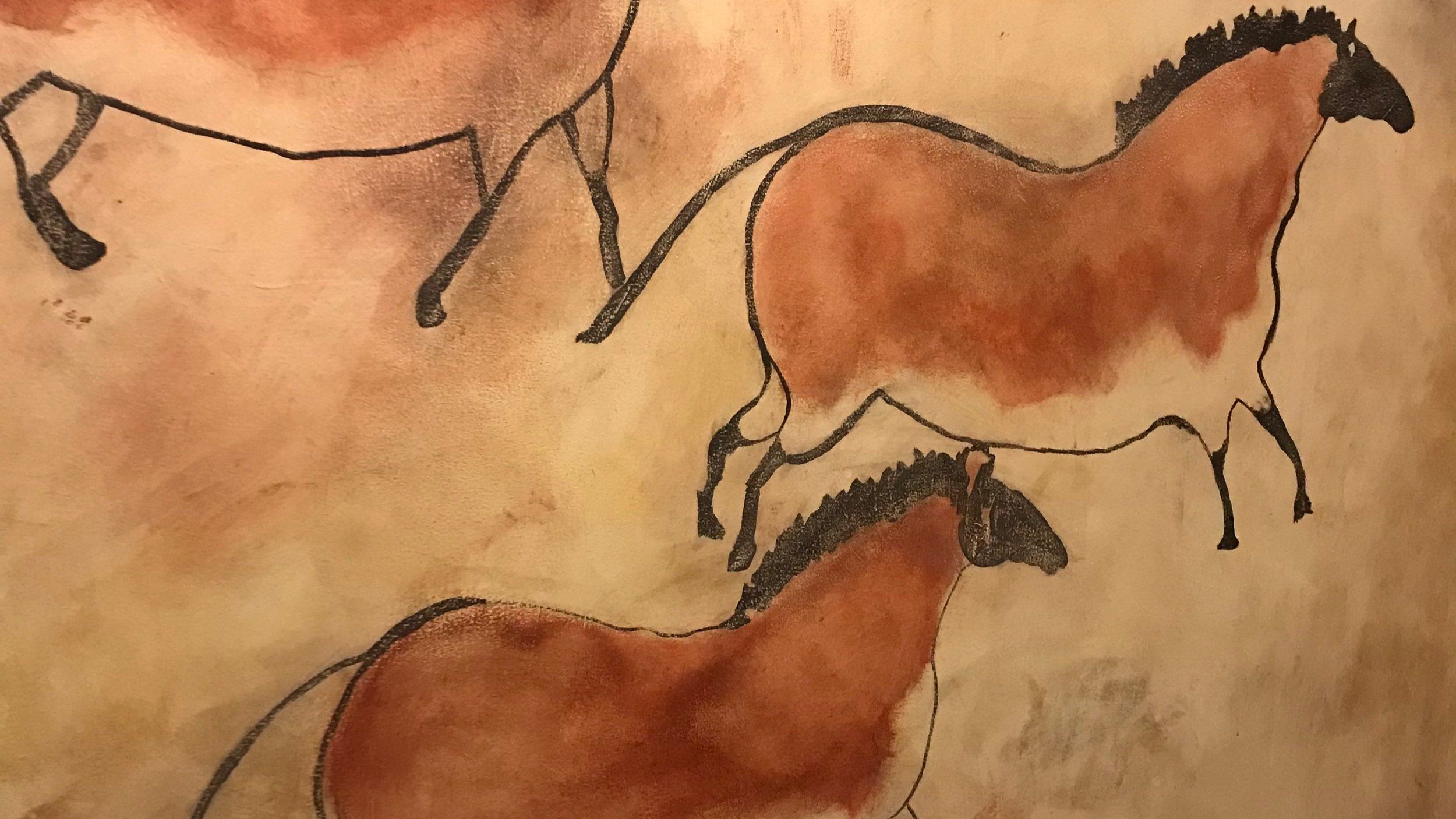 Horses painted in ochre in the style of prehistoric cave art on a school hallway wall