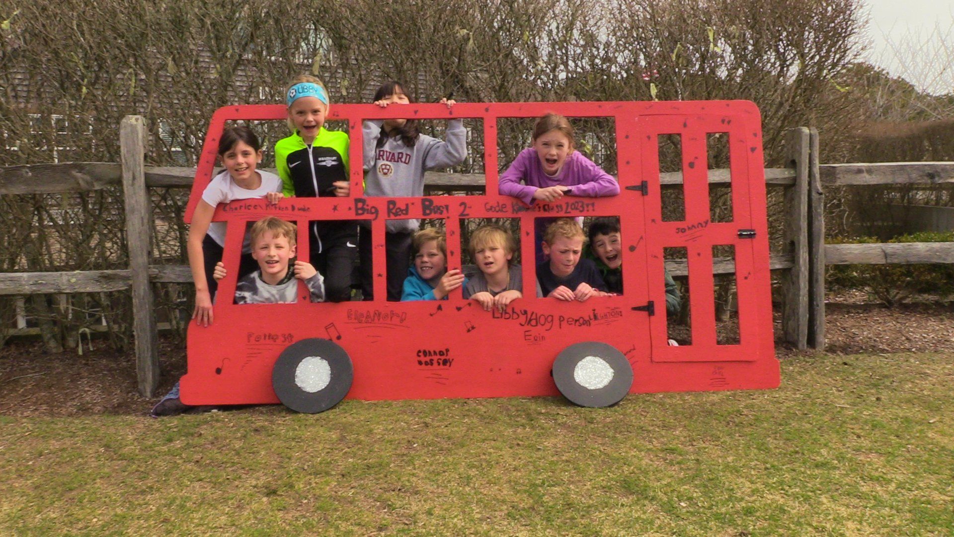 Students lean out of the windows of a painted red cut-out bus